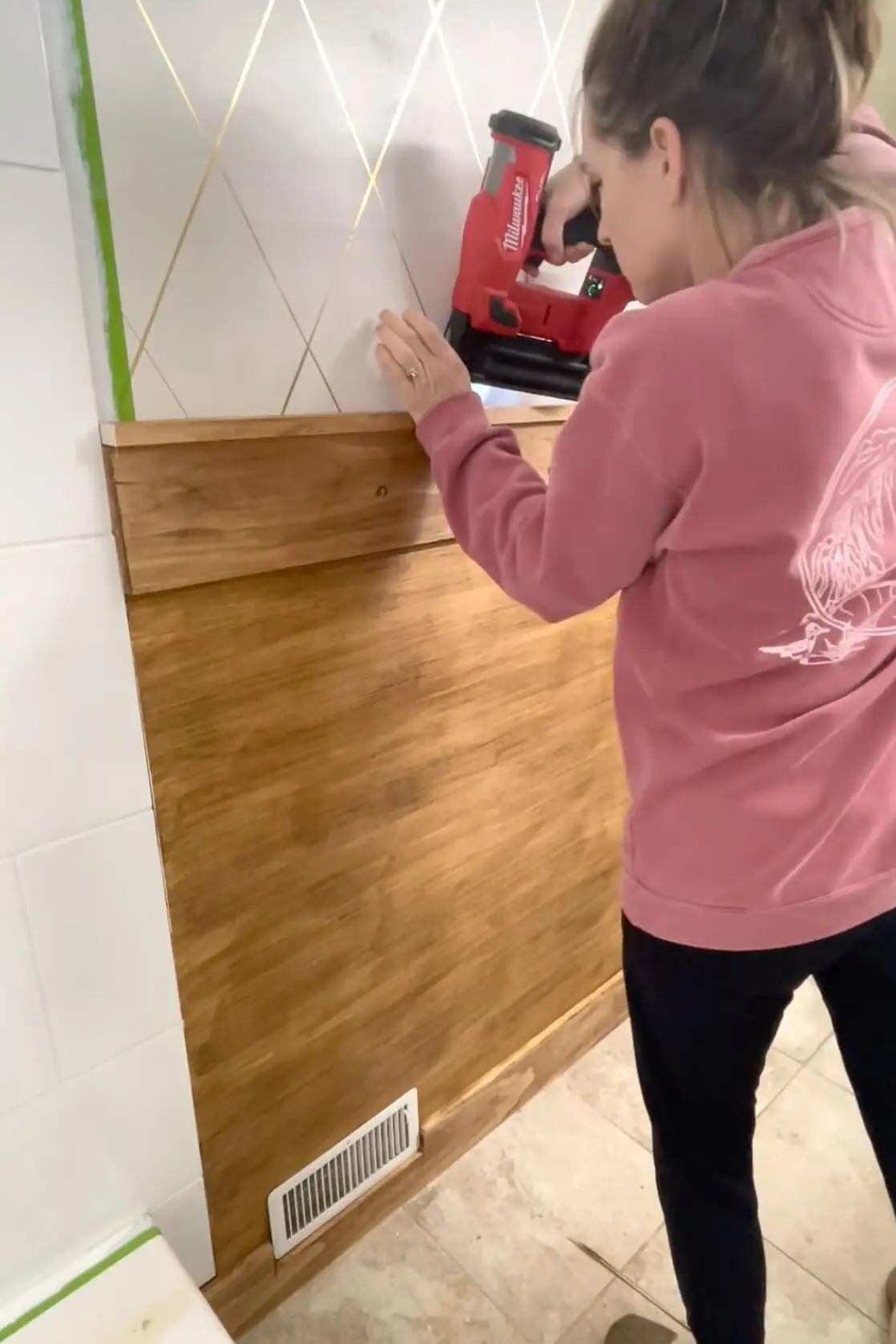 Using a brad nailer to attach trim to a board and batten bathroom wall. 